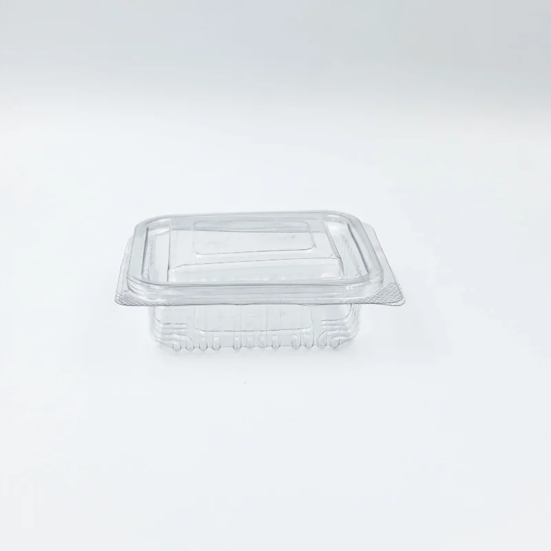 Transparent plastic food storage container with a matching lid on a light surface, viewed from above.
