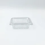 Transparent plastic food storage container with a matching lid on a light surface, viewed from above.