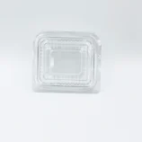 Clear plastic clamshell container lid seen from above, with ridged edge and nesting compartments visible inside.