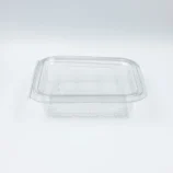 Transparent plastic food storage container with lid on a white background on a flat surface.