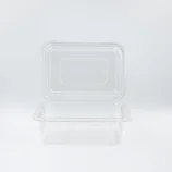 Clear rectangular plastic food storage container with lid on a white surface, seen from above.