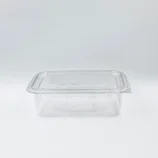 Clear plastic food storage container with a snap-on lid on a white surface, empty and viewed from the side/top edge.