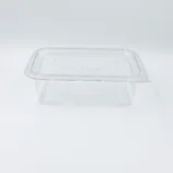 Transparent rectangular plastic food storage container with a matching lid, viewed from above-left on a white surface.