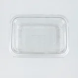 Close-up of a clear rectangular plastic clamshell lid with ridged edges on a light gray background.